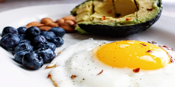 plate with sunny side up egg, blueberries, and half avocado